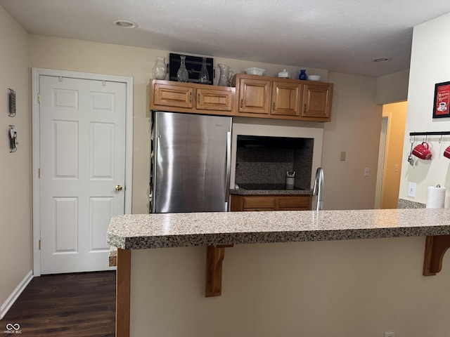 1626 N Nieman Dr, Greensburg, IN 47240 - kitchen with dark wood finished floors, a breakfast bar, freestanding refrigerator, brown cabinetry, and recessed lighting