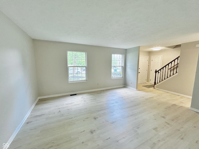 6839 Antelope Dr, Indianapolis, IN 46278 - unfurnished living room featuring stairway, light wood-type flooring, and a textured ceiling