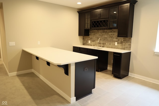13044 Moorland Ln, Carmel, IN 46074 - kitchen featuring a kitchen breakfast bar, tasteful backsplash, light countertops, a peninsula, and glass insert cabinets