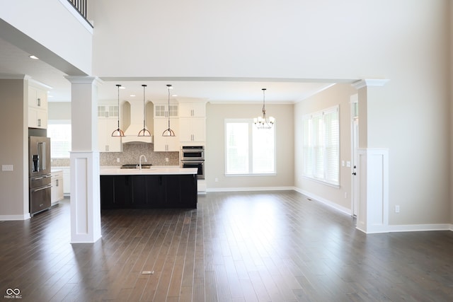 13044 Moorland Ln, Carmel, IN 46074 - kitchen with stainless steel appliances, custom range hood, light countertops, an island with sink, and dark wood finished floors