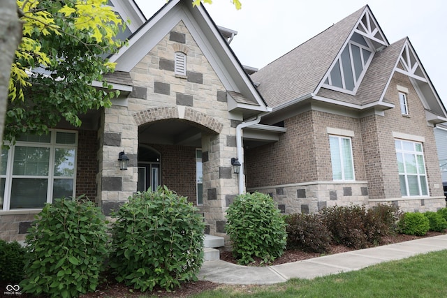 13044 Moorland Ln, Carmel, IN 46074 - view of exterior entry featuring roof with shingles, brick siding, and stone siding