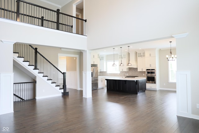 13044 Moorland Ln, Carmel, IN 46074 - living area featuring dark wood-style floors, a chandelier, a high ceiling, stairway, and ornamental molding