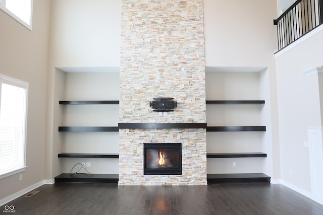 13044 Moorland Ln, Carmel, IN 46074 - unfurnished living room featuring a towering ceiling, wood finished floors, healthy amount of natural light, and a stone fireplace