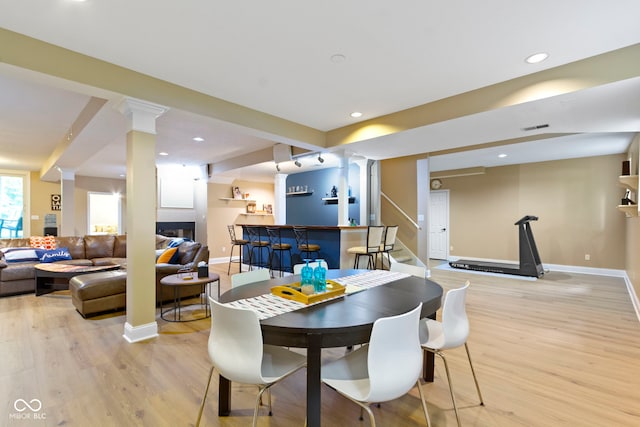 12214 Ridgeside Rd, Indianapolis, IN 46256 - dining space featuring a bar, light wood-style flooring, decorative columns, recessed lighting, and stairway