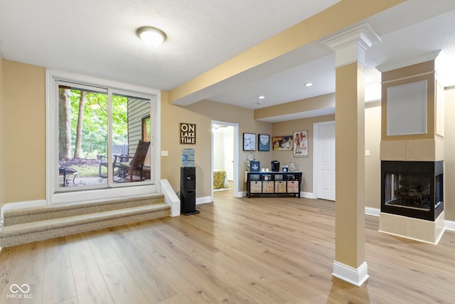 12214 Ridgeside Rd, Indianapolis, IN 46256 - living room featuring light wood-style flooring, a tiled fireplace, decorative columns, recessed lighting, and stairway
