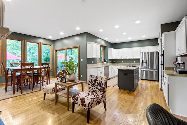 12214 Ridgeside Rd, Indianapolis, IN 46256 - kitchen with appliances with stainless steel finishes, light wood-type flooring, a kitchen island, white cabinets, and light stone counters