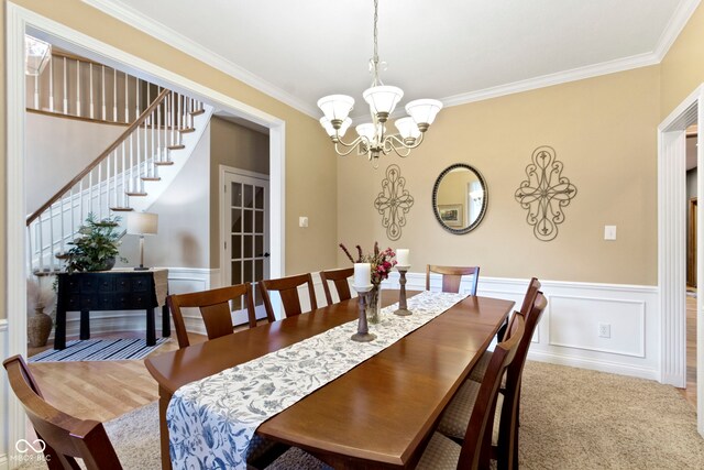 12214 Ridgeside Rd, Indianapolis, IN 46256 - carpeted dining room featuring ornamental molding, a chandelier, stairs, a wainscoted wall, and a decorative wall