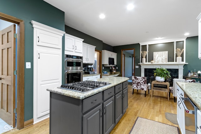 12214 Ridgeside Rd, Indianapolis, IN 46256 - kitchen with gray cabinetry, stainless steel appliances, white cabinets, a center island, and light wood finished floors