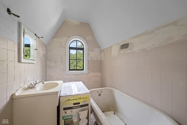 2421 W 39th St, Indianapolis, IN 46228 - bathroom featuring tile walls, a tub to relax in, vanity, and lofted ceiling