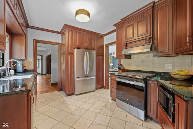 2421 W 39th St, Indianapolis, IN 46228 - kitchen featuring appliances with stainless steel finishes, tasteful backsplash, arched walkways, dark stone counters, and crown molding