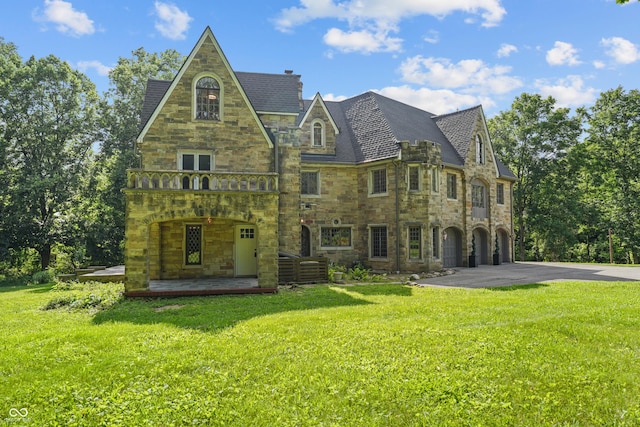 2421 W 39th St, Indianapolis, IN 46228 - back of house with stone siding, driveway, a yard, a chimney, and an attached garage