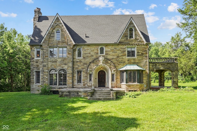 2421 W 39th St, Indianapolis, IN 46228 - tudor house featuring a chimney, stone siding, a front lawn, and a shingled roof
