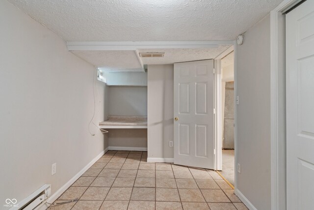 4517 E 16th St, Indianapolis, IN 46201 - unfurnished bedroom with a textured ceiling, light tile patterned flooring, and baseboard heating