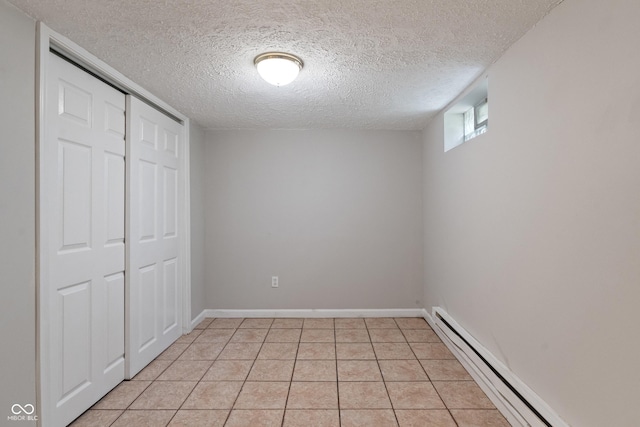 4517 E 16th St, Indianapolis, IN 46201 - unfurnished bedroom with a baseboard heating unit, a textured ceiling, a closet, and light tile patterned floors