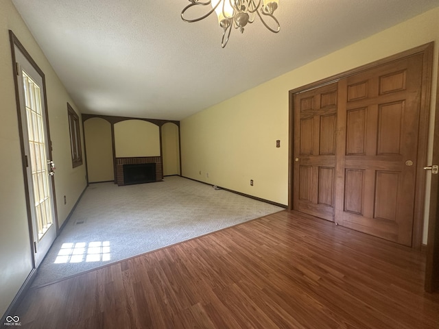 1289 Woodcreek Dr, Greenwood, IN 46142 - unfurnished living room with a brick fireplace, a chandelier, wood finished floors, a textured ceiling, and carpet