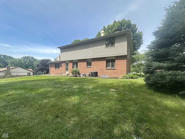 1289 Woodcreek Dr, Greenwood, IN 46142 - rear view of property with brick siding, a yard, and a chimney