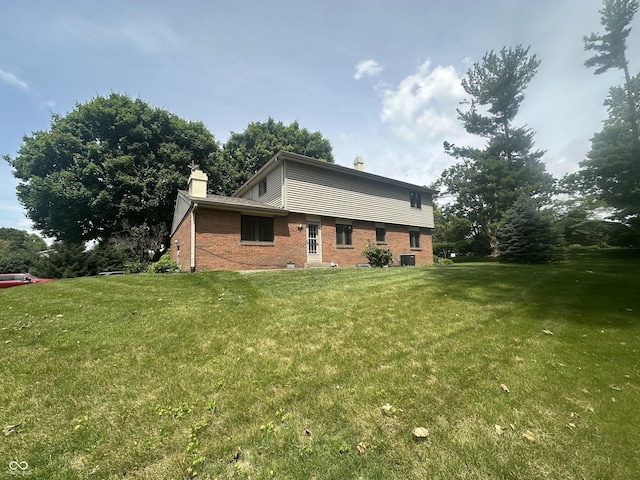 1289 Woodcreek Dr, Greenwood, IN 46142 - view of home's exterior with a chimney, brick siding, and a lawn
