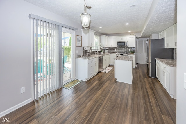 14052 Rayners Ln, Fishers, IN 46037 - kitchen featuring stainless steel appliances, a textured ceiling, backsplash, dark wood finished floors, and a center island