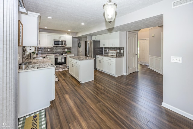 14052 Rayners Ln, Fishers, IN 46037 - kitchen featuring appliances with stainless steel finishes, a textured ceiling, decorative backsplash, white cabinets, and a center island
