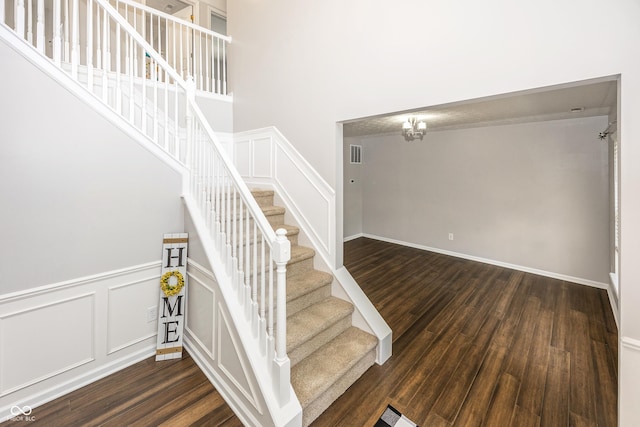 14052 Rayners Ln, Fishers, IN 46037 - staircase with wood finished floors, a chandelier, a towering ceiling, a decorative wall, and a wainscoted wall