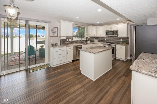 14052 Rayners Ln, Fishers, IN 46037 - kitchen with stainless steel appliances, a textured ceiling, a kitchen island, tasteful backsplash, and white cabinets