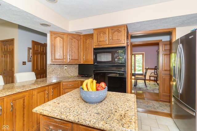 10518 Courageous Dr, Indianapolis, IN 46236 - kitchen featuring black appliances, brown cabinetry, light stone countertops, tasteful backsplash, and a center island