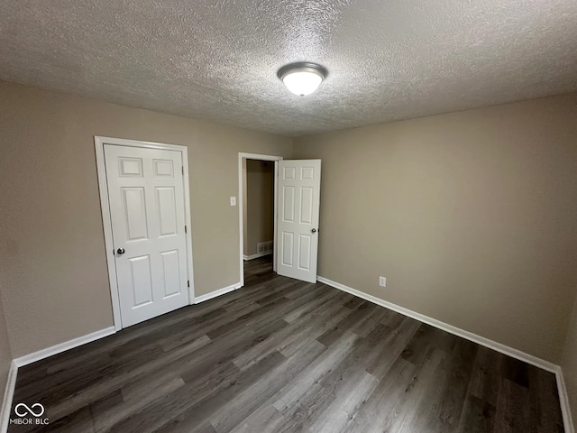 115 Hugo St, Indianapolis, IN 46229 - unfurnished bedroom with dark wood-type flooring and a textured ceiling