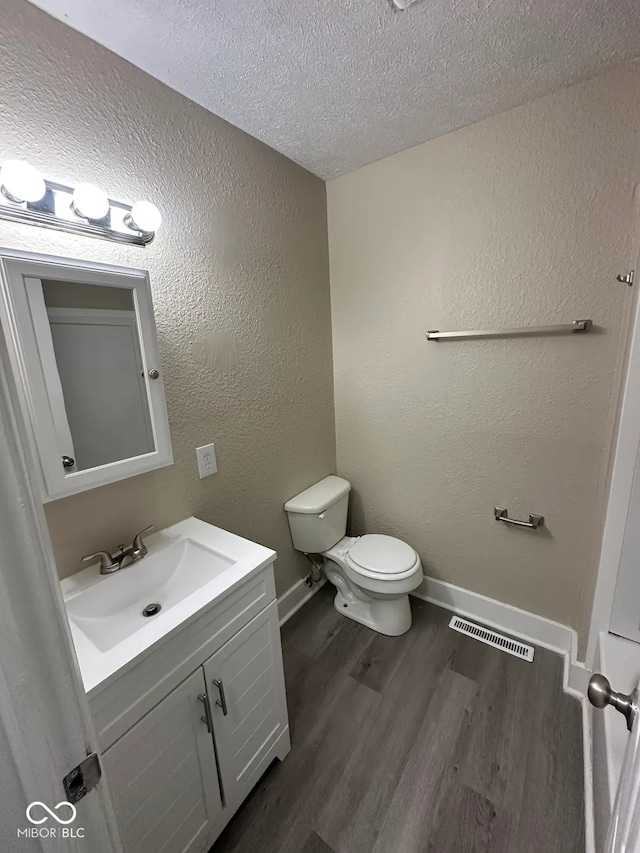 115 Hugo St, Indianapolis, IN 46229 - half bathroom with wood finished floors, vanity, a textured ceiling, and a textured wall
