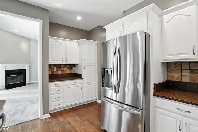 6183 Whitetail Run, Greenwood, IN 46143 - kitchen with stainless steel fridge, white cabinets, decorative backsplash, dark wood finished floors, and a fireplace with flush hearth