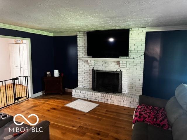 3815 Briar Rdg, Monrovia, IN 46157 - living area featuring a textured ceiling, wood finished floors, ornamental molding, and a brick fireplace