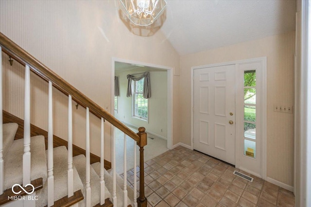 8315 Union Chapel Rd, Indianapolis, IN 46240 - foyer with lofted ceiling, stairway, a chandelier, wallpapered walls, and light stone finish flooring