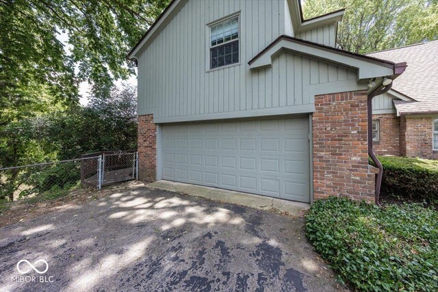 8315 Union Chapel Rd, Indianapolis, IN 46240 - view of home's exterior featuring brick siding, asphalt driveway, an attached garage, and board and batten siding