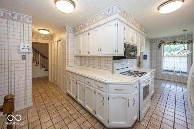 8315 Union Chapel Rd, Indianapolis, IN 46240 - kitchen with gas range gas stove, wallpapered walls, white cabinetry, light countertops, and a textured ceiling