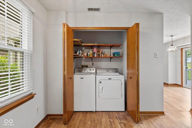 4609 Framington Ct, Indianapolis, IN 46254 - laundry area with washing machine and dryer, light wood-style flooring, a textured ceiling, and a chandelier