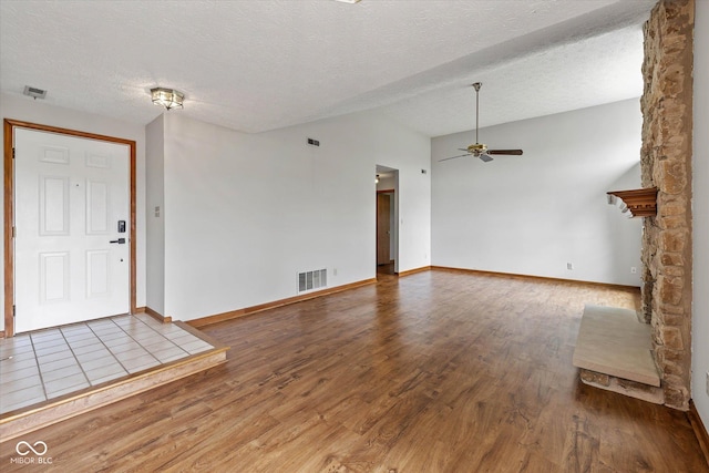 4609 Framington Ct, Indianapolis, IN 46254 - unfurnished living room featuring wood finished floors, a ceiling fan, lofted ceiling, a textured ceiling, and a stone fireplace