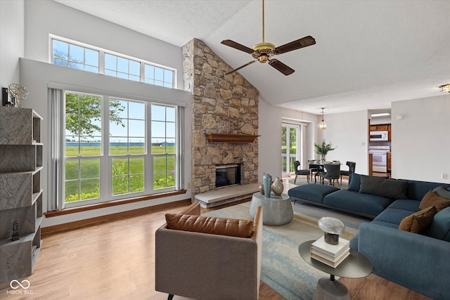 4609 Framington Ct, Indianapolis, IN 46254 - living area with a ceiling fan, wood finished floors, a textured ceiling, a stone fireplace, and high vaulted ceiling
