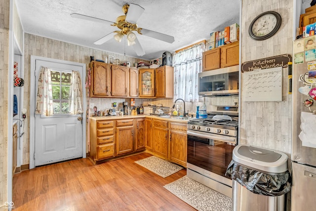 850 Duane St, Franklin, IN 46131 - kitchen with appliances with stainless steel finishes, brown cabinetry, a ceiling fan, light wood-type flooring, and light countertops
