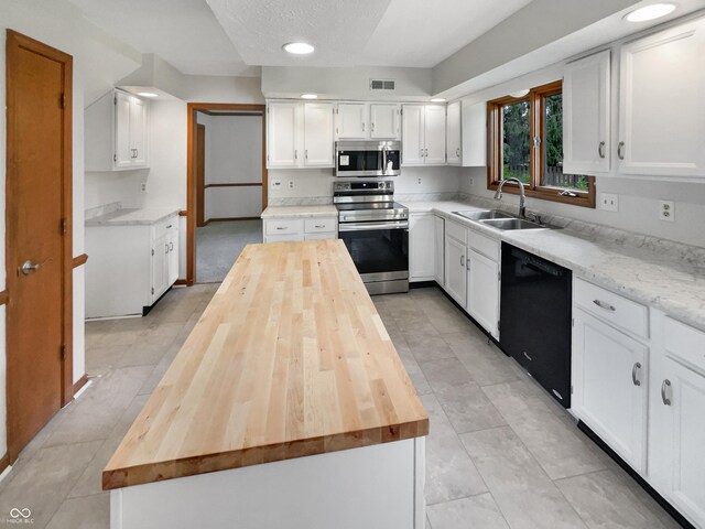 757 Winter Way, Carmel, IN 46032 - kitchen with stainless steel appliances, wood counters, a center island, white cabinetry, and light tile patterned floors