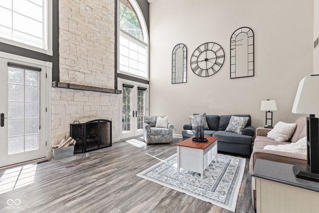 4465 W Woodbridge Ln, New Palestine, IN 46163 - living room featuring wood finished floors, a high ceiling, french doors, and a stone fireplace