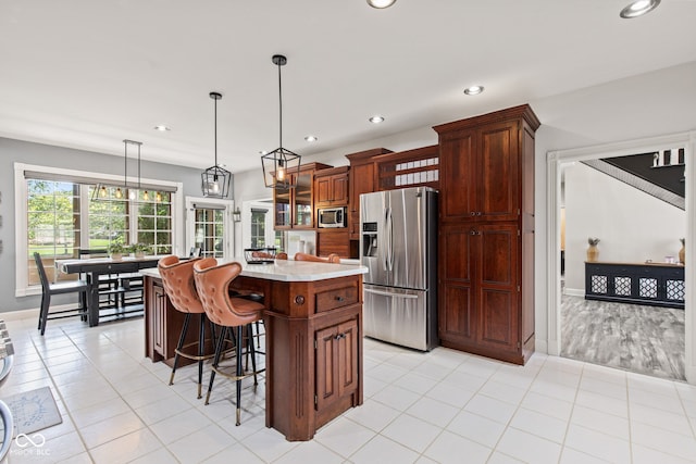 4465 W Woodbridge Ln, New Palestine, IN 46163 - kitchen featuring appliances with stainless steel finishes, light countertops, a kitchen island, recessed lighting, and a kitchen bar
