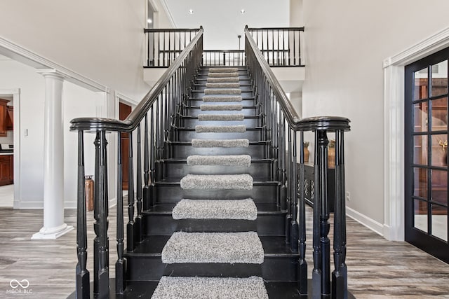 4465 W Woodbridge Ln, New Palestine, IN 46163 - stairs featuring wood finished floors, a high ceiling, and decorative columns