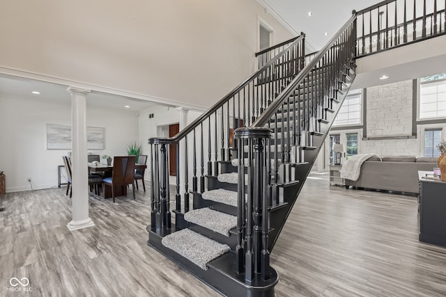 4465 W Woodbridge Ln, New Palestine, IN 46163 - staircase featuring a towering ceiling, decorative columns, wood finished floors, crown molding, and recessed lighting