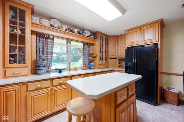 5081 N 500 W, Fairland, IN 46126 - kitchen featuring black fridge, light countertops, a center island, glass insert cabinets, and light tile patterned floors