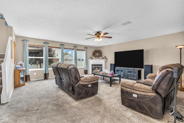 7047 Lancaster Ln, Avon, IN 46123 - living room featuring ceiling fan, a textured ceiling, carpet, a glass covered fireplace, and stairs