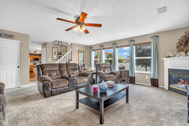 7047 Lancaster Ln, Avon, IN 46123 - living area featuring stairway, carpet, ceiling fan, a glass covered fireplace, and a textured ceiling