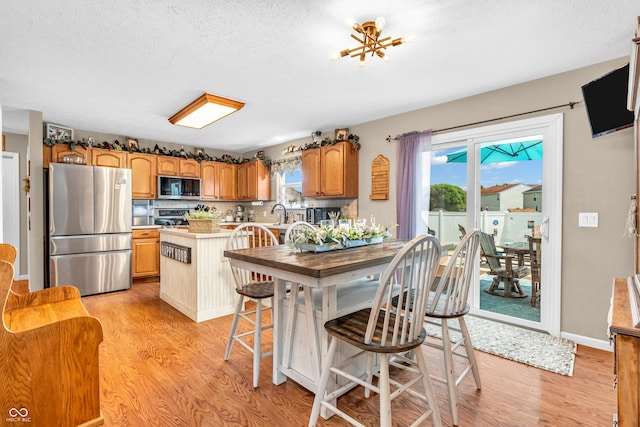 7047 Lancaster Ln, Avon, IN 46123 - kitchen featuring appliances with stainless steel finishes, light wood finished floors, healthy amount of natural light, and a textured ceiling
