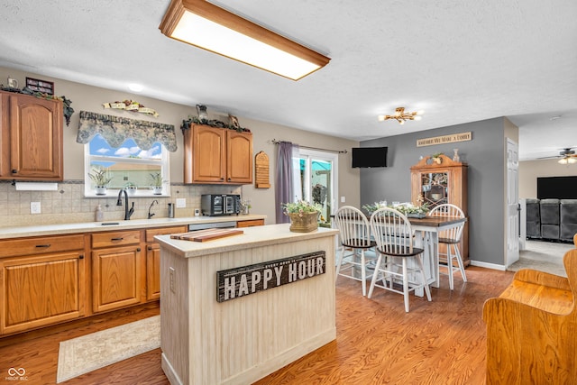 7047 Lancaster Ln, Avon, IN 46123 - kitchen featuring light countertops, a center island, backsplash, light wood-style flooring, and a textured ceiling