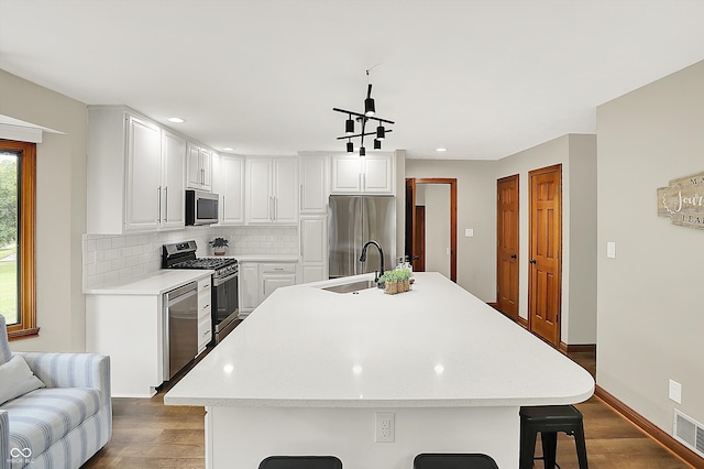 369 Rodeo Dr, Indianapolis, IN 46217 - kitchen with appliances with stainless steel finishes, dark wood-style flooring, tasteful backsplash, a breakfast bar, and light countertops