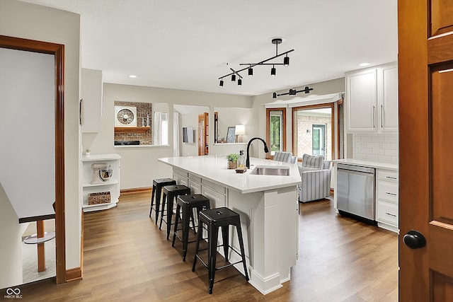 369 Rodeo Dr, Indianapolis, IN 46217 - kitchen featuring dishwasher, a kitchen bar, light countertops, wood finished floors, and a center island with sink