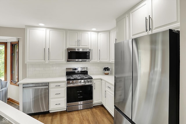 369 Rodeo Dr, Indianapolis, IN 46217 - kitchen featuring stainless steel appliances, light countertops, dark wood finished floors, white cabinetry, and tasteful backsplash